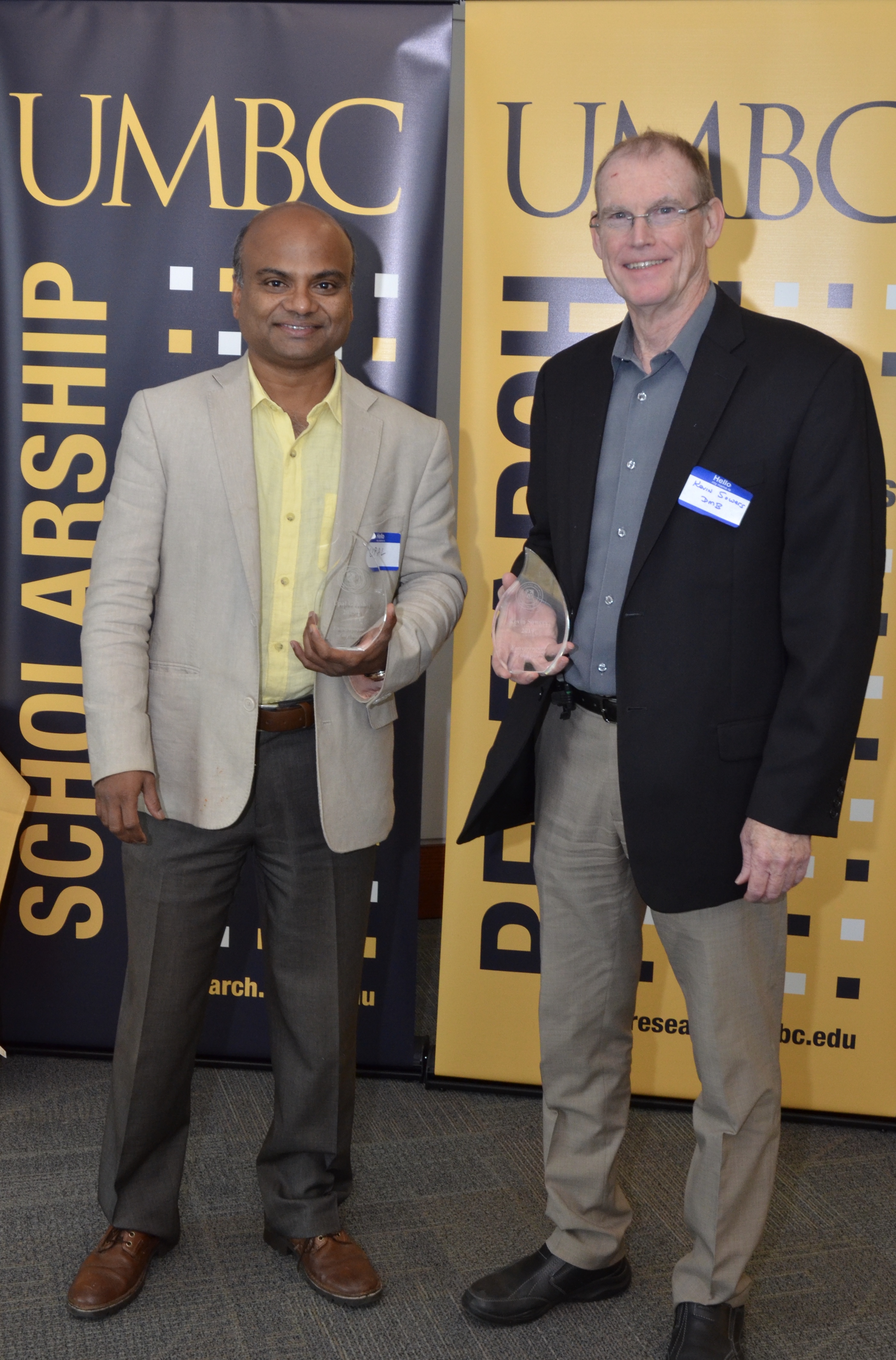 Kevin Sowers and Upal Ghosh hold clear glass trophies