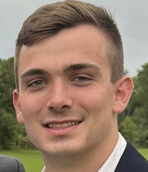 Kevin Dyke smiling in a field wearing a white shirt and sport coat