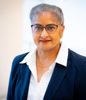 A professional headshot of Nina Lamba in the IMET lobby