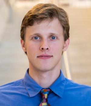 A professional headshot of Max in the IMET lobby