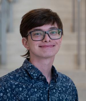 A professional headshot of Sam in the IMET lobby