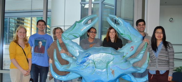 Students and an instructor posed around a crab statue