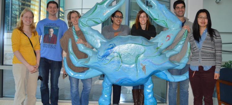 Students and an instructor posed around a crab statue