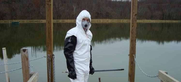 Kevin Sowers wearing PPE in front of water at a contaminated site