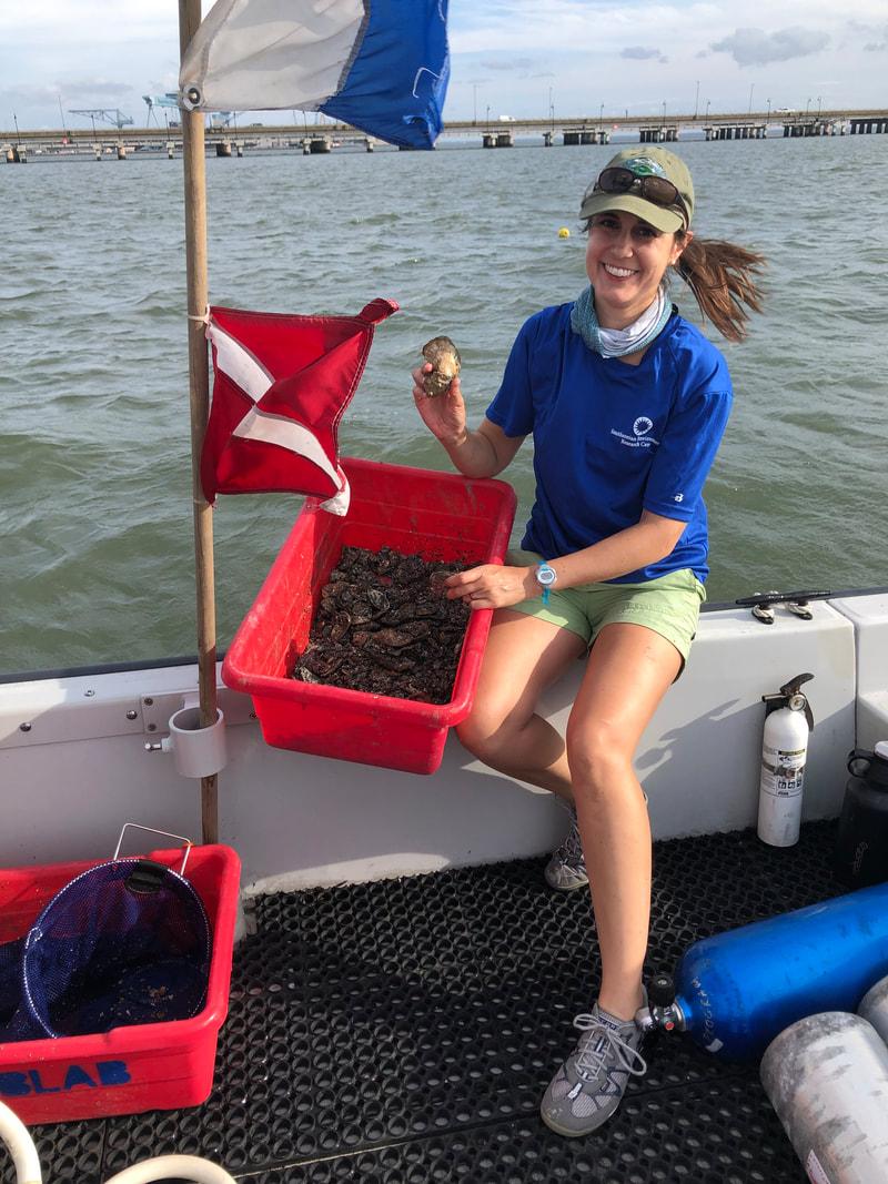 Allison Tracy sitting on a boat holding a bucket of oyster samples