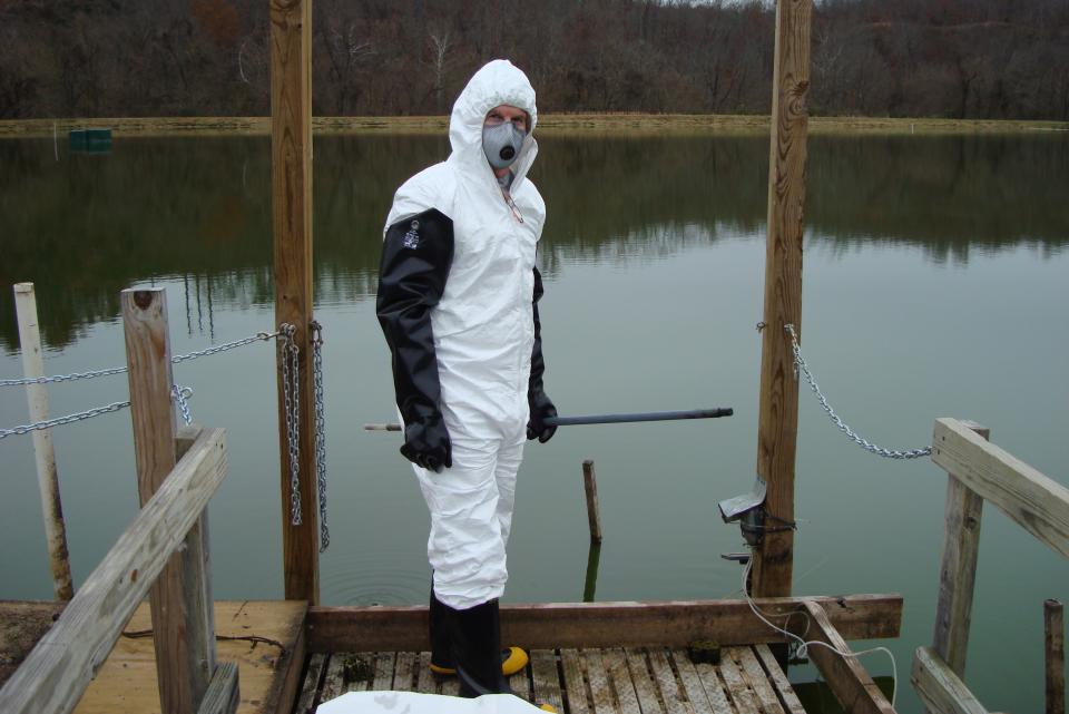 Kevin Sowers wearing PPE in front of water at a contaminated site