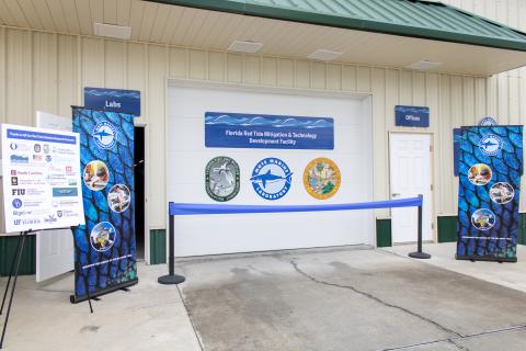 Ribbon and signs in front of Red Tide Facility entrance