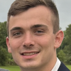 Kevin Dyke smiling in a field wearing a white shirt and sport coat